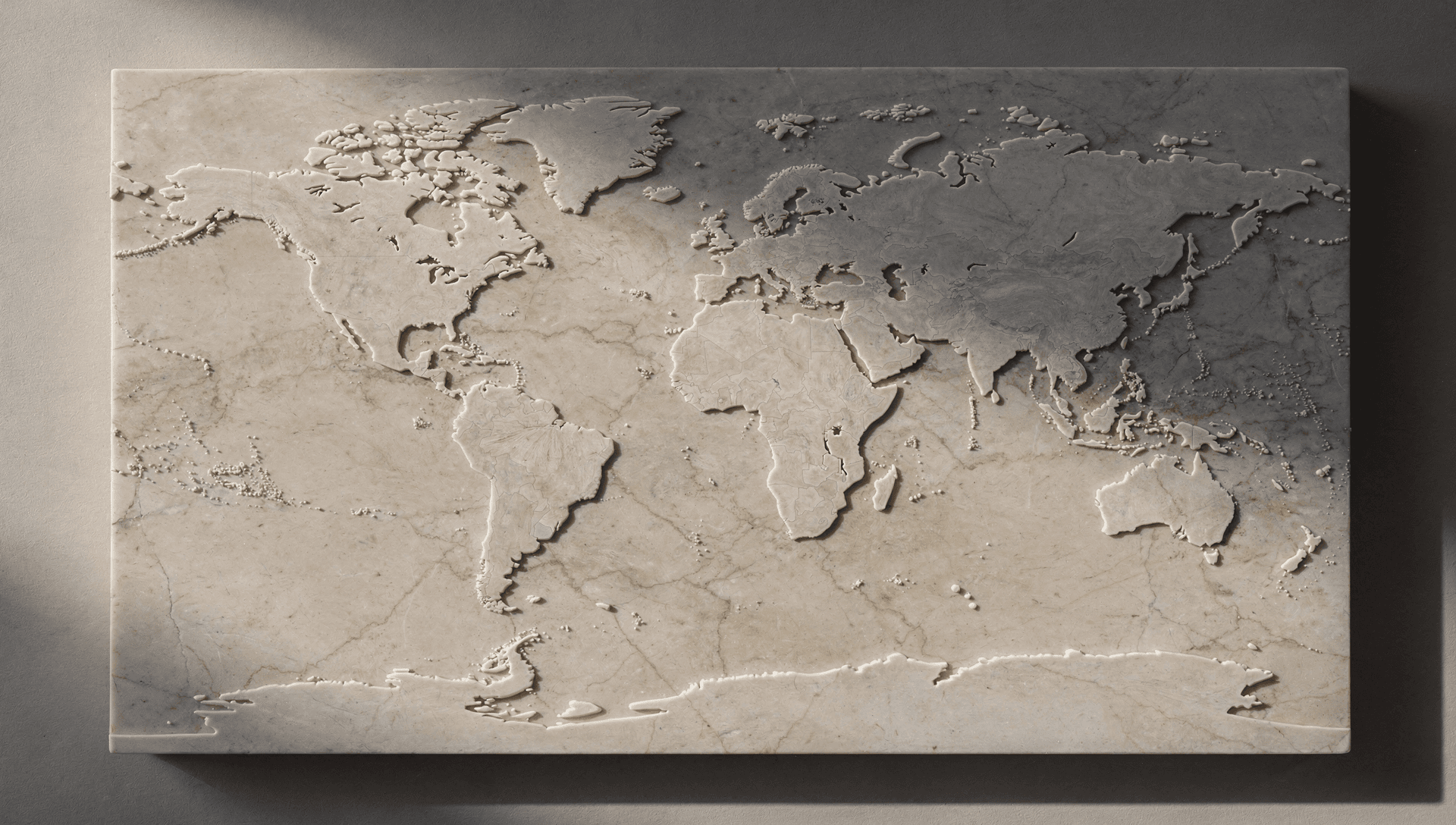 A world map carved in low relief into a slab of pale marble, in low raking light.